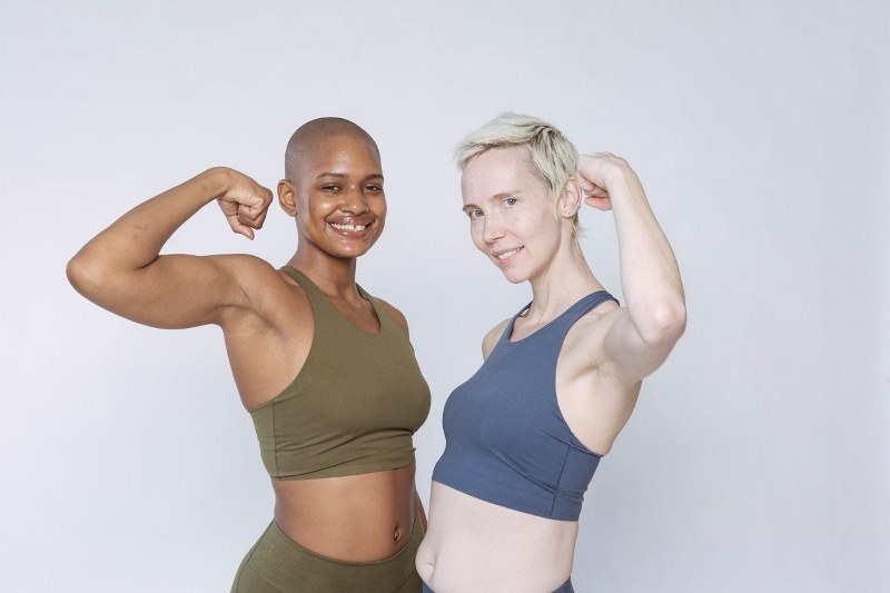 Multiracial women pumping biceps muscle in studio