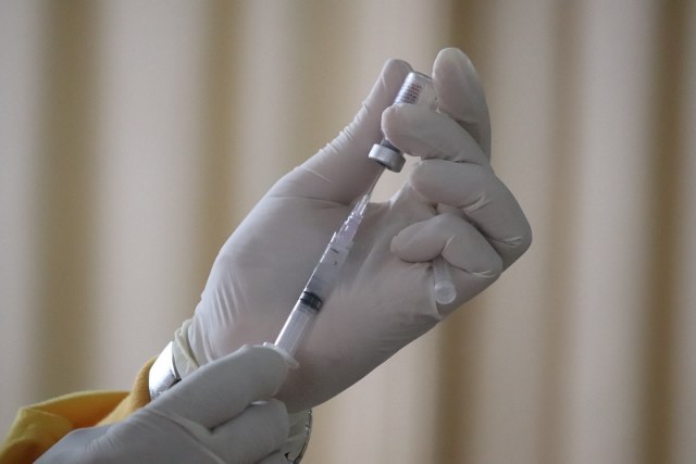 person wearing doctor's gloves holding an injection