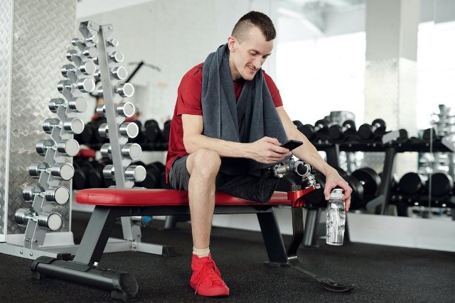 man in red and black polo shirt and black pants sitting sitting on red and black bench keeps him fit by doing exercise in 2022