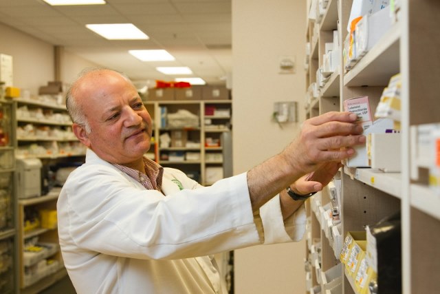 a male pharmacist is selecting nolvadex from the display case in pharmacy